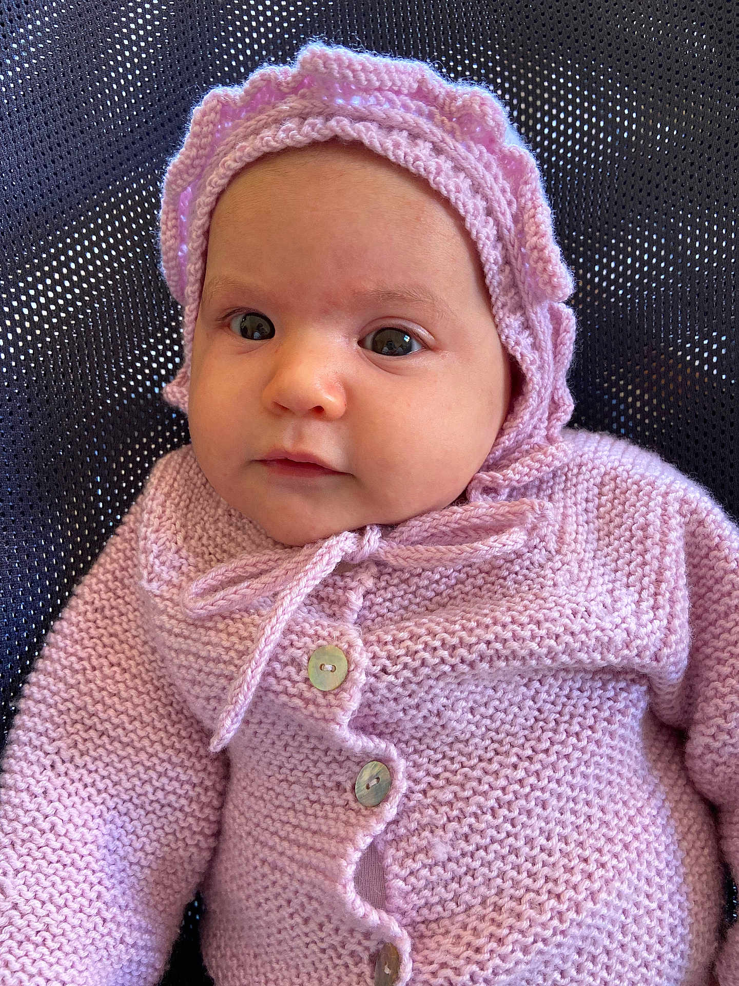 Irina a rejoint le concours — aidez-le/la à gagner de superbes lots ! baby, infant, knitted_clothing, bonnet, purple, cute, face, portrait, child, young, buttoned_sweater, warm_clothing, soft_texture, looking, seated, indoors, closeup, headwear, person, newborn