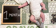 Grayson is registered to the contest to win money with this photo: baby, infant, one_month, onesie, blanket, quilt, milestone_chalkboard, chalkboard, name_banner, grayson, puppy_pattern, dog_print, socks, garland_beads, laying_down, smile, portrait, indoor, cute, newborn
