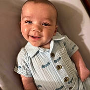 Grayson joined the competition — help win amazing prizes! baby, blue_clothing, child, closeup, comfortable, cushion, cute, face, happy, head, indoor, infant, lying_down, person, portrait, relaxed, smiling, soft_lighting, wooden_buttons, young_child