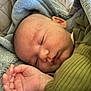 baby, newborn, infant, sleeping, blanket, bedding, closed_eyes, hand, cheek, ear, skin, soft_texture, cozy, portrait, closeup, indoors, swaddle, clothing, peaceful, nursery