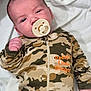 baby, infant, newborn, pacifier, camouflage, onesie, blanket, lying_down, hand, face, head, calm, cute, portrait, baby_clothing, soft_fabric, nursery, small_person, sleepy, human