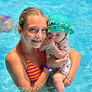 Grayson is registered to the contest to win money with this photo: baby, braces, child, cute, family, fun, happy, hat, holding, outdoor, people, playful, pool, smile, summer, sunlight, swimming, swimsuit, vacation, water