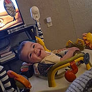 Grayson is registered to the contest to win money with this photo: baby, smiling, activity_center, toy, indoor, child, happy, face, furniture, television, living_room, lion_toy, seat, playtime, person, home, wall, floor, clothing, infant