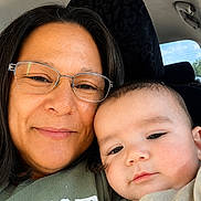 Grayson is registered to the contest to win money with this photo: baby, car_interior, casual_clothing, closeup, daylight, face, family, glasses, happy, head, indoors, mother_and_child, person, portrait, seat, skin, smile, together, window, woman