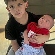 Alaiden joined the competition — help win amazing prizes! child, baby, siblings, holding, bench, picnic_table, outdoor, brick_wall, cup_with_straw, toddler, infant, portrait, red_shirt, striped_shorts, black_socks, shorts, serious_expression, sleepy_baby, hands, legs