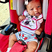 Ramirra is registered to the contest to win money with this photo: baby, infant, child, car_seat, sitting, portrait, smiling, bow, bib, disney, strawberries, striped_clothing, red, pink, white, harness, seat_belt, outdoor, vehicle, safe