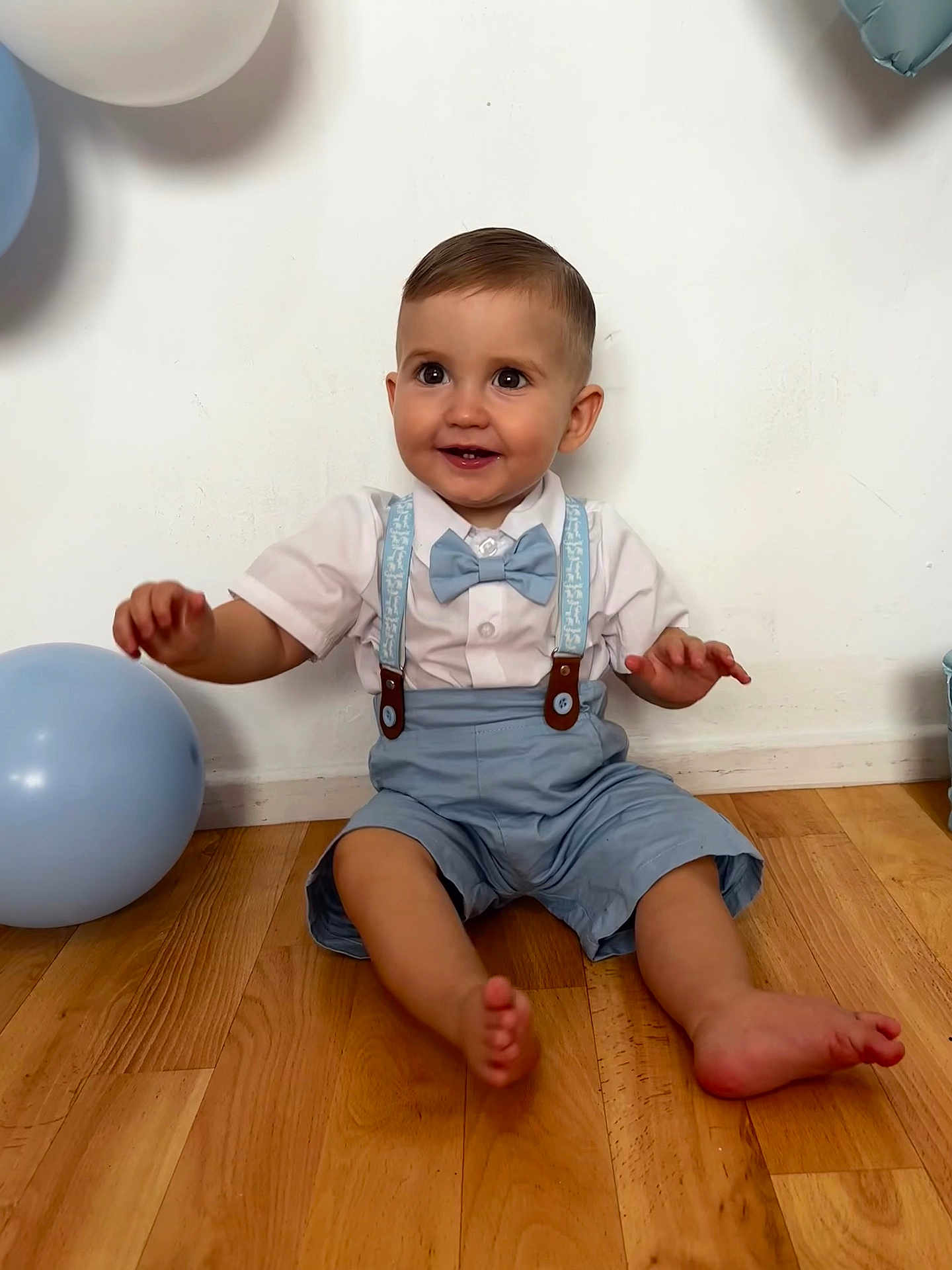 Lawson a rejoint le concours — aidez-le/la à gagner de superbes lots ! toddler, child, smiling, bow_tie, suspenders, shorts, white_shirt, balloons, indoor, wooden_floor, happy, cute, portrait, baby, hands, feet, sitting, floor, person, celebration