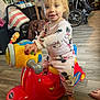 toddler, child, toy_scooter, indoor, playtime, pajamas, minnie_mouse, floor, footwear, smile, face, hand, toy, wheel, furniture, bag, flooring, foot, person, happy