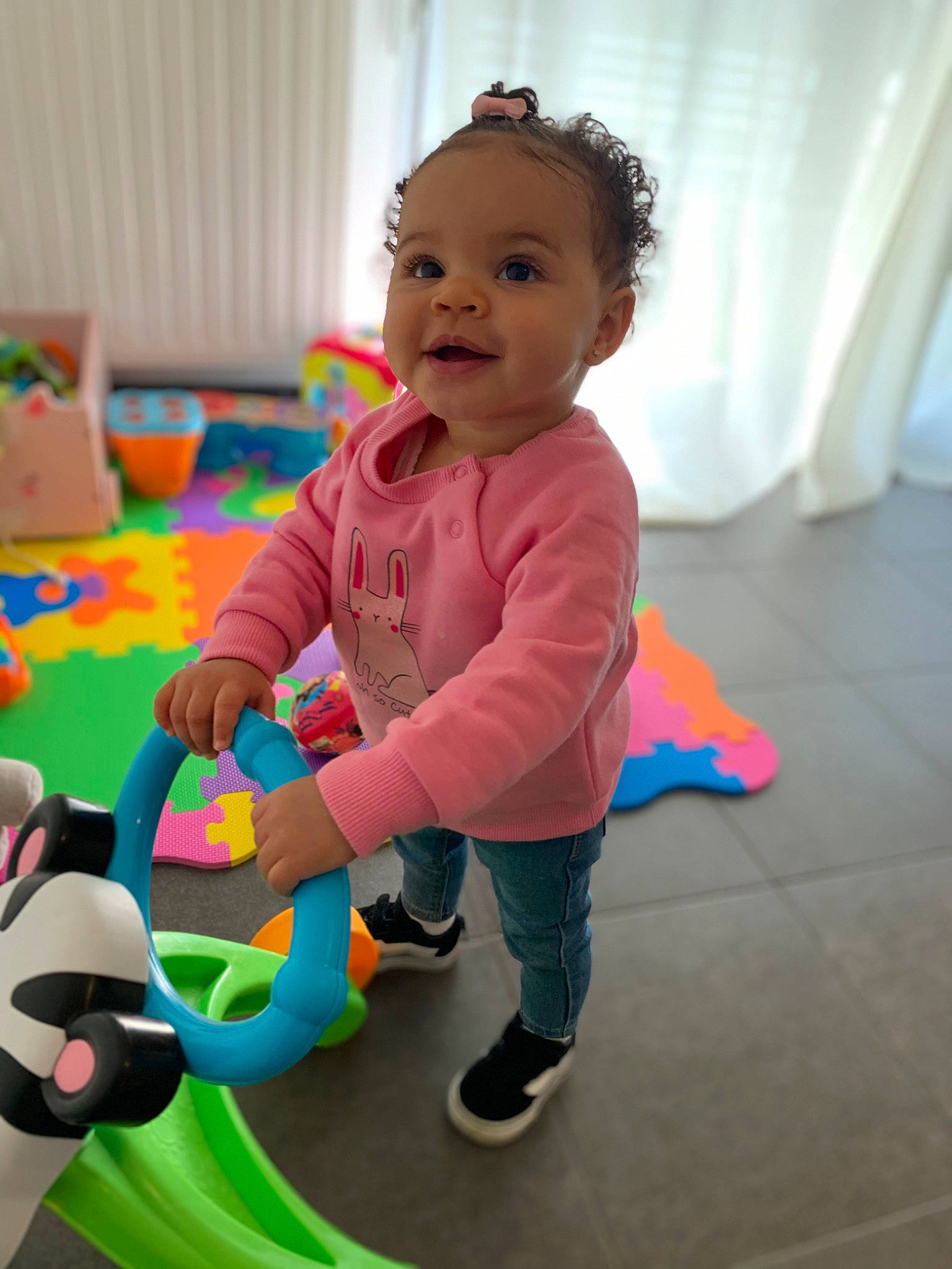 Maelyss a rejoint le concours — aidez-le/la à gagner de superbes lots ! baby, baby_playing_with_toys, baby_products, baby_toddler_clothing, baby_toys, child, curtain, flooring, fun, happy, leisure, person, play, room, sitting, smile, stuffed_toy, toddler, toy, toy_vehicle