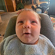 Kaysen joined the competition — help win amazing prizes! baby, infant, face, close_up, bib, towel, blanket, indoor, living_room, carpet, furniture, car_seat, table, chair, wood_floor, portrait, cute, chubby_cheeks, eyes_up, soft_texture