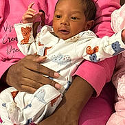 Jiraiya is registered to the contest to win money with this photo: baby, infant, child, newborn, onesie, dinosaur_pattern, hand, adult, pink_sweatshirt, holding, portrait, cute, smiling, face, skin, clothing, cozy, indoor, person, baby_girl