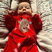 Aurora joined the competition — help win amazing prizes! baby, infant, red_onesie, reindeer_design, floral_pattern, cushion, blanket, soft_texture, cozy, lying_down, hands, face, cute, holiday_theme, indoors, portrait, child, warm, comfortable, sleepwear