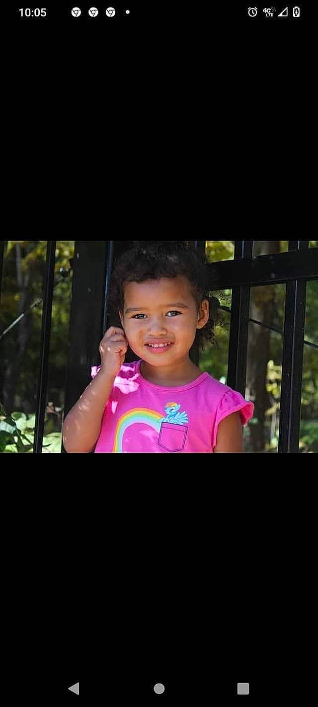Annsleigh is registered to the contest to win money with this photo: child, electronic_device, face, flash_photography, fun, gesture, grass, hairstyle, happy, iris, joy, leisure, magenta, person, photo_caption, recreation, sitting, sleeve, smile, t_shirt
