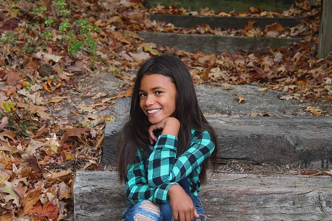 Adaliah joined the competition — help win amazing prizes! beauty, black_hair, brown_hair, child, fawn, flash_photography, grass, happy, joy, leaf, leisure, long_hair, pattern, people_in_nature, person, plaid, plant, sitting, smile, tree