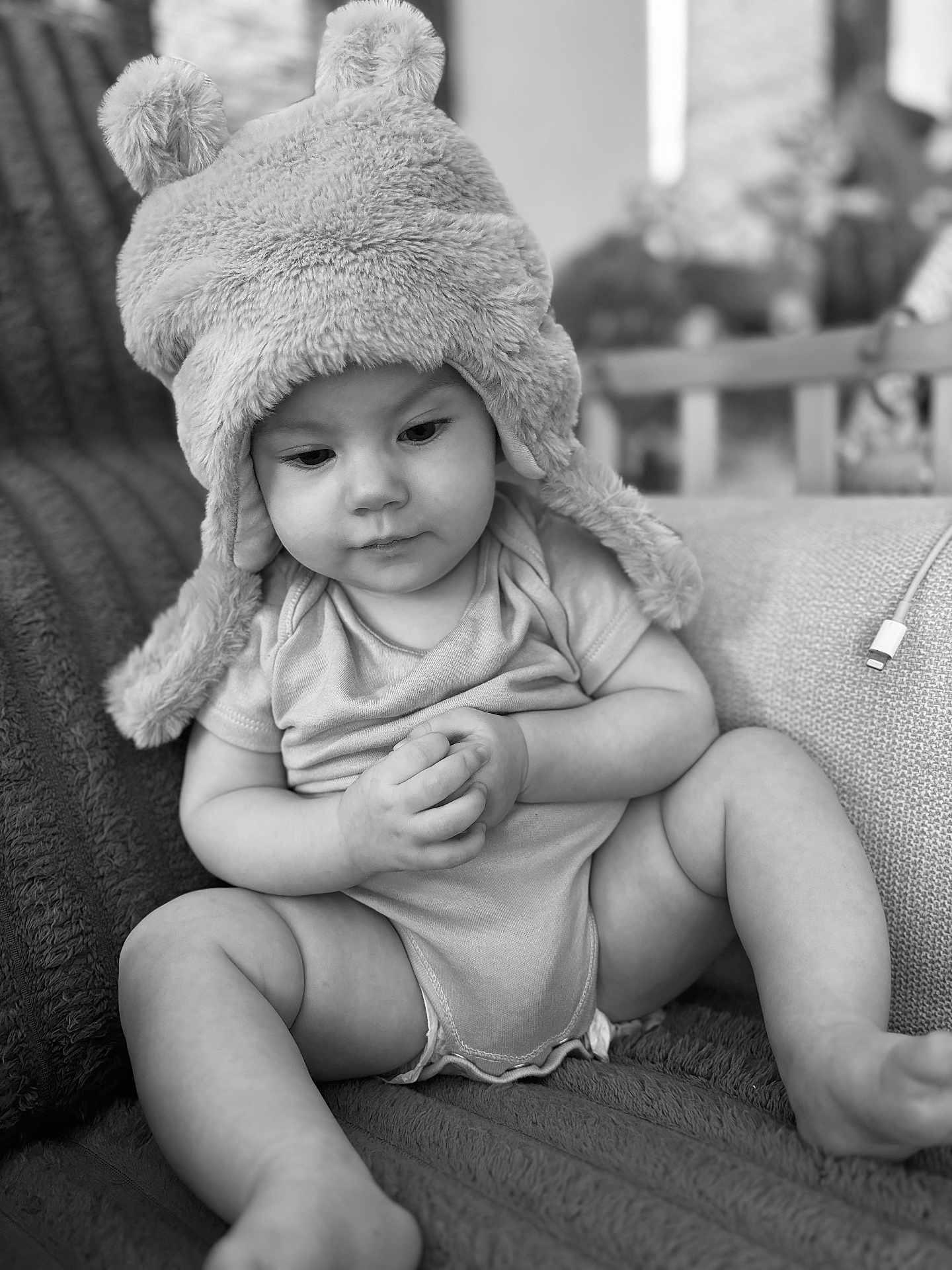 Malilou a rejoint le concours — aidez-le/la à gagner de superbes lots ! baby, child, infant, hat, fuzzy_hat, pom_poms, sitting, blanket, indoors, couch, monochrome, black_and_white, cute, portrait, clothing, hands, legs, expression, soft_texture, cozy