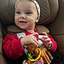 baby, child, car_seat, headband, toy, pacifier, red_clothing, polka_dot, smiling, happy, infant, seat_belt, cute, playful, indoor, close_up, face, hands, polka_dots, comfort