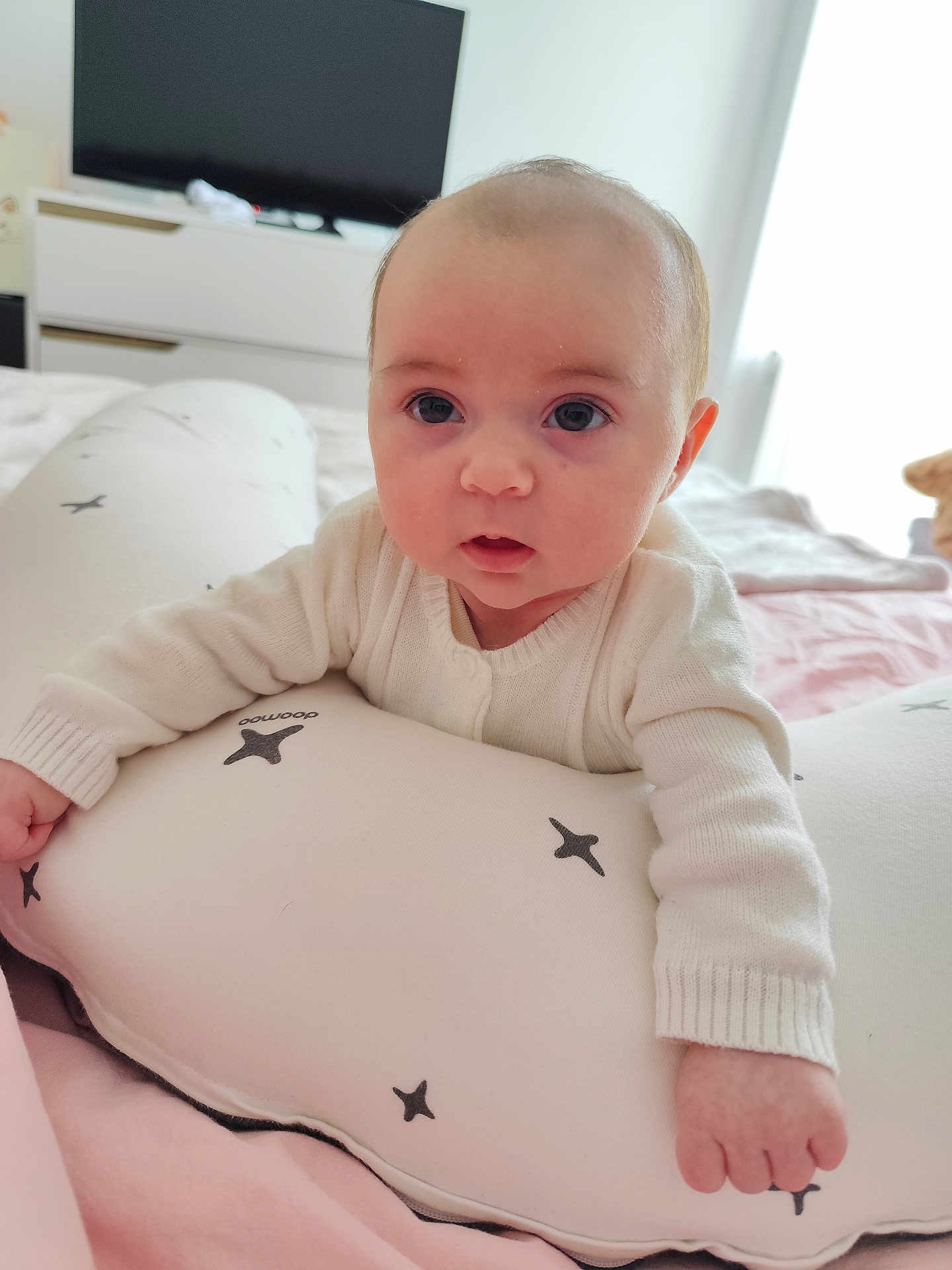 Anna a rejoint le concours — aidez-le/la à gagner de superbes lots ! baby, infant, child, face, eyes, pillow, star_pattern, blanket, bed, bedding, bedroom, dresser, television, onesie, white_clothing, portrait, close_up, cute, hand, stuffed_animal