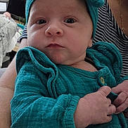 Anaë a rejoint le concours — aidez-le/la à gagner de superbes lots ! baby, child, infant, teal_clothing, headband, person, portrait, indoor, striped_shirt, adult_arm, hand, face, eyes, living_room, furniture, television, photography, closeup, cute, expression