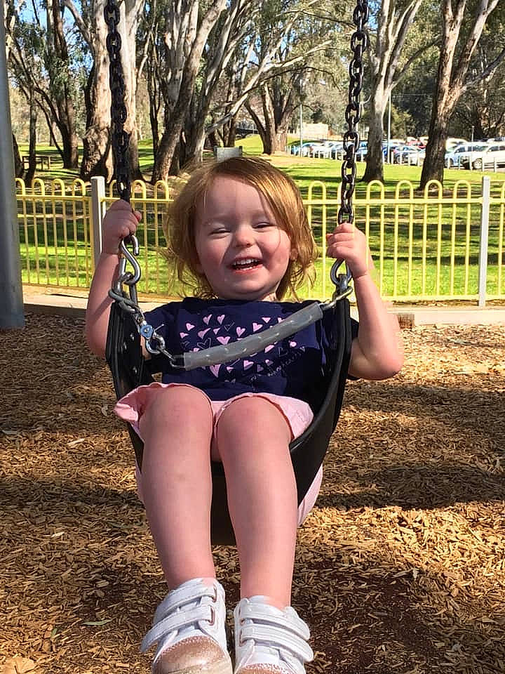 Scarlett joined the competition — help win amazing prizes! arm, child, facial_expression, fun, happy, joy, leg, outdoor_play_equipment, person, play, playground, public_space, recreation, smile, swing, toddler, tree