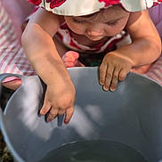 Livina a rejoint le concours — aidez-le/la à gagner de superbes lots ! toddler, child, hat, bucket, water, hand, fingers, blanket, outdoor, sunlight, curious, baby, summer, play, skin, closeup, flower_pattern, pink, candid, exploration
