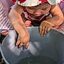 toddler, child, hat, bucket, water, hand, fingers, blanket, outdoor, sunlight, curious, baby, summer, play, skin, closeup, flower_pattern, pink, candid, exploration