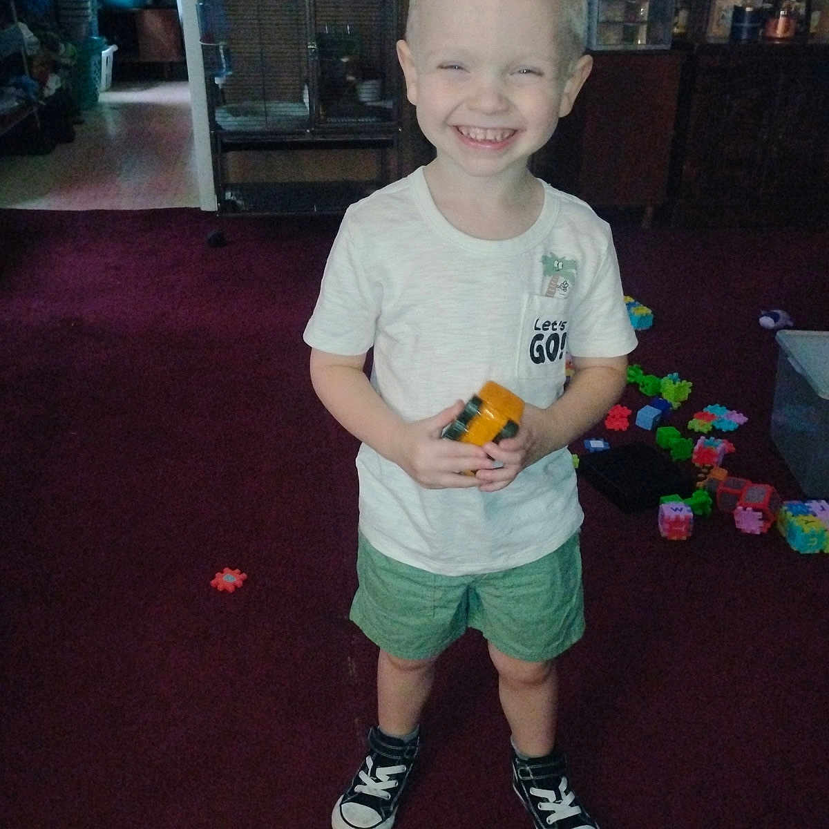 Westin Foote is registered to the contest to win money with this photo: carpet, casual_clothing, child, floor, furniture, hair, happy, indoor, mohawk, person, plastic_toys, play, room, shorts, smiling, sneakers, standing, storage, toy, tshirt