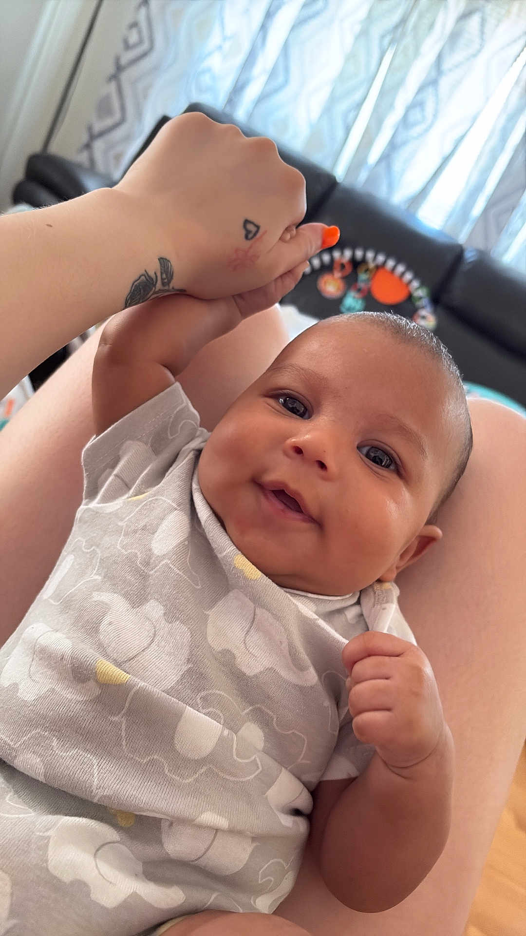 Jrue joined the competition — help win amazing prizes! baby, infant, smiling, hand, tattoo, nail_polish, onesie, elephant_pattern, person, legs, living_room, couch, curtains, skin, happy, closeup, indoor, holding_hand, cute, portrait