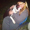 person, dog, outdoor, night, chair, hugging, red_eye, grass, pet, casual_clothing, blurry, flash, long_hair, sitting, affection, chain_collar, dark_background, beanie, close_up, love
