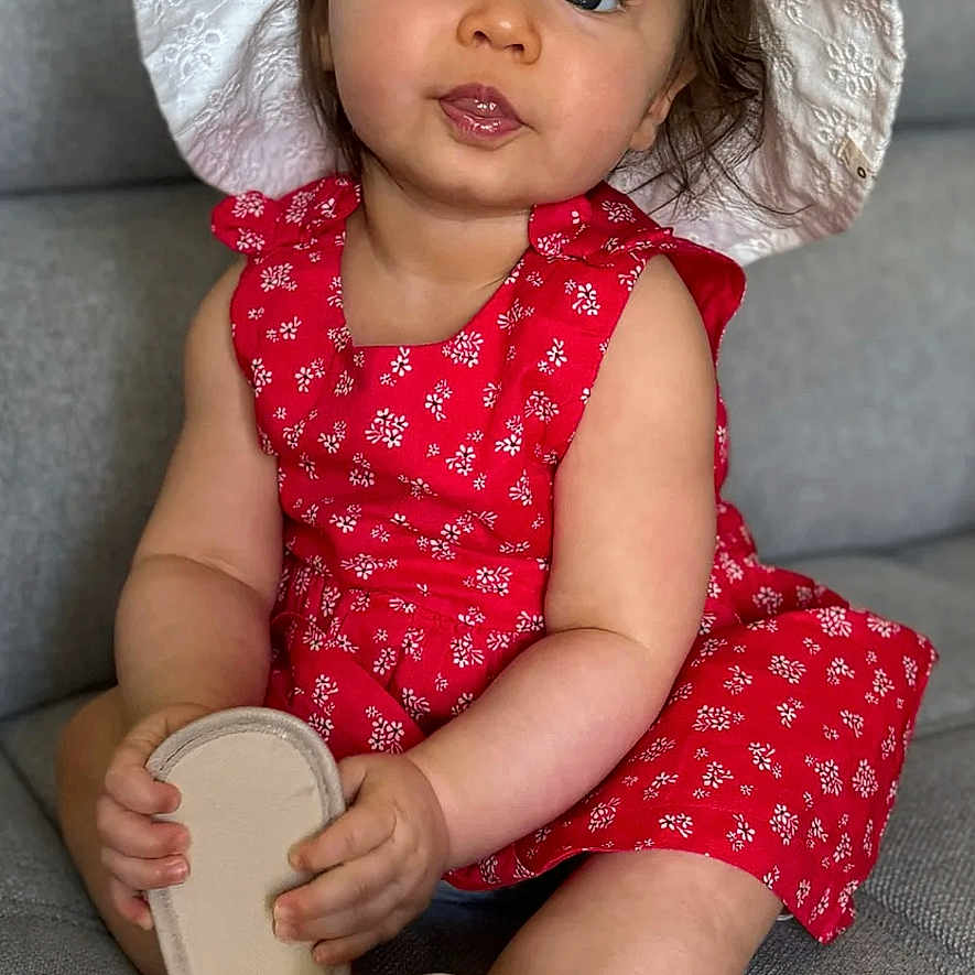 Ambre participe au concours pour gagner de l'argent avec cette photo : baby, child, couch, curious, cute, dress, face, footwear, hands, hat, home, indoor, legs, red_dress, shoe, sitting, smile, sole, toddler, white_hat