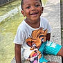 Noëlan a rejoint le concours — aidez-le/la à gagner de superbes lots ! child, smiling, outdoor, canal, stone_ledge, lion_king, tshirt, shorts, park, bridge, trees, water, sunny, happy, person, casual_clothing, daytime, nature, recreation, leisure