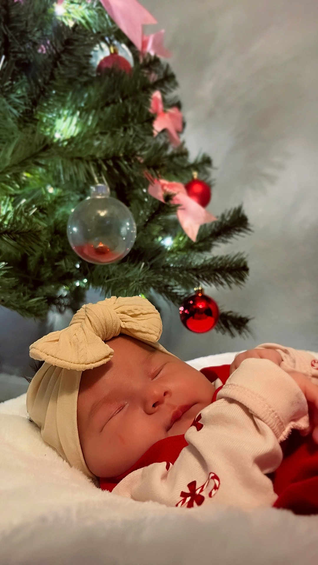 Ily is registered to the contest to win money with this photo: baby, sleeping, headband, bow, blanket, christmas_tree, ornament, red, decorations, holiday, soft_lighting, indoors, closeup, infant, cute, festive, peaceful, cozy, child, holiday_season