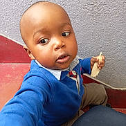 Assaf a rejoint le concours — aidez-le/la à gagner de superbes lots ! blue_sweater, bread, candid, casual_clothing, child, curious, face, hand, head, indoors, looking_away, person, portrait, real_photo, red_floor, sitting, stairs, textured_wall, toddler, young_child