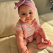 Salomé Santos joined the competition — help win amazing prizes! baby, infant, headband, pink, striped_clothing, suspenders, couch, leather, indoor, sunlight, footwear, bracelet, cute, smiling, child, person, skin, hand, face, happy