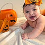 Salomé Santos joined the competition — help win amazing prizes! baby, smiling, orange_bow, pumpkin, halloween, blanket, cute, infant, happy, face, portrait, child, holiday, decor, costume_accessory, indoor, celebration, cute_expression, joy, festive