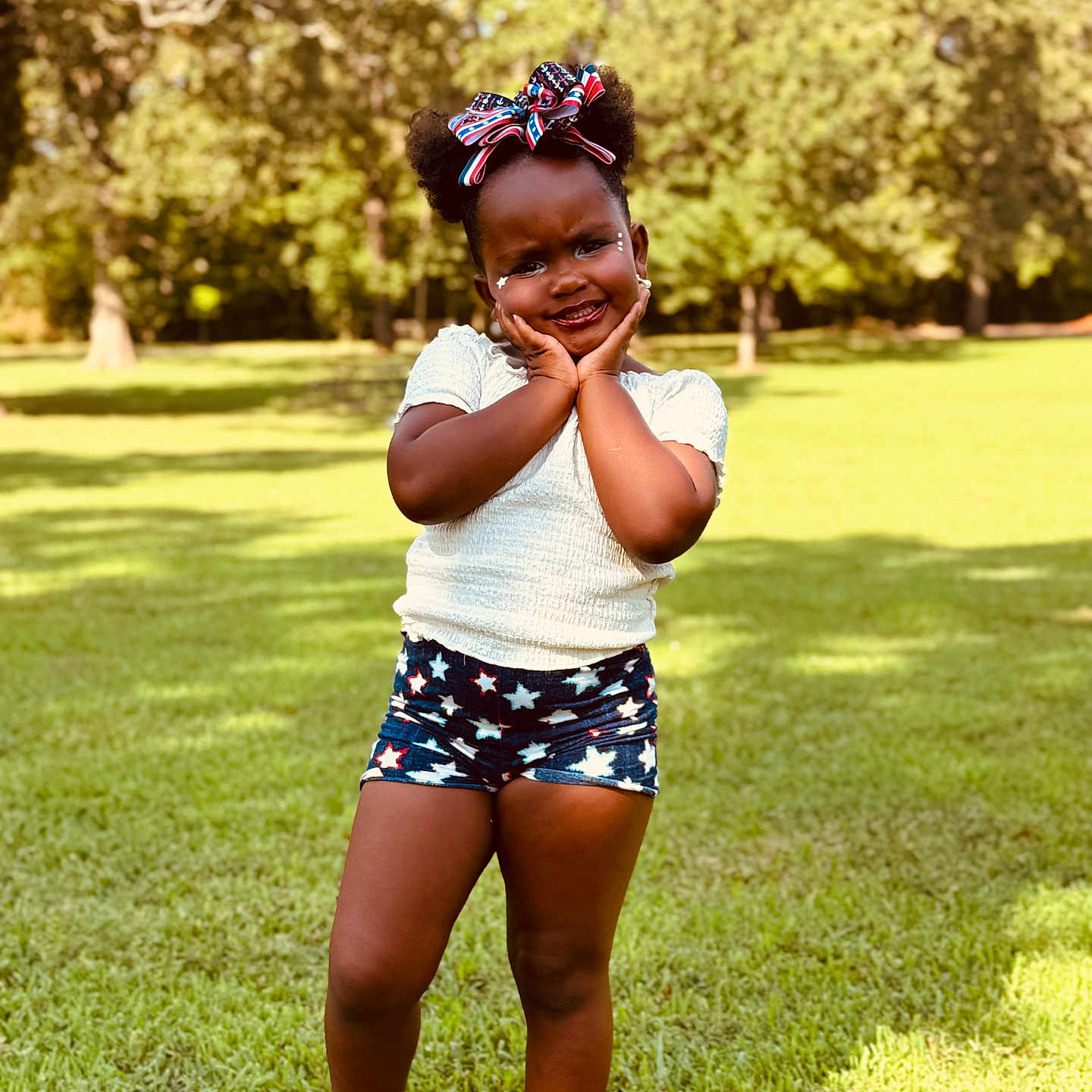 Tinala joined the competition — help win amazing prizes! bow, child, cute, daytime, fashion, girl, grass, greenery, hair_puffs, happy, nature, outdoor, playful, portrait, shorts, smiling, standing, summer, sunlight, white_top