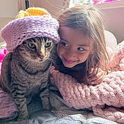 Boots joined the competition — help win amazing prizes! cat, tabby_cat, knitted_hat, child, blanket, indoor, smiling, cute, window, toy, bed, home_decor, girl, affection, cozy, soft_texture, furniture, curtain, friendship, portrait