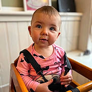 Maddison joined the competition — help win amazing prizes! toddler, child, baby, high_chair, pink_shirt, suspenders, blue_eyes, indoor, wooden_furniture, curious_expression, drool, person, portrait, casual_clothing, cute, young_child, face, hands, seated, cozy