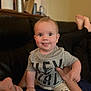 Luke is registered to the contest to win money with this photo: baby, child, tongue_out, smile, person, couch, indoor, hand, face, clothing, shorts, tshirt, adult, holding, playful, blurred_background, skin, head, foot, living_room