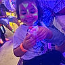 Joelee joined the competition — help win amazing prizes! child, face_paint, smiling, toy, indoor, party, colorful, purple_lighting, blue_lighting, people, clothing, wristband, happy, sitting, curly_hair, event, table, jeans, floor, decorations