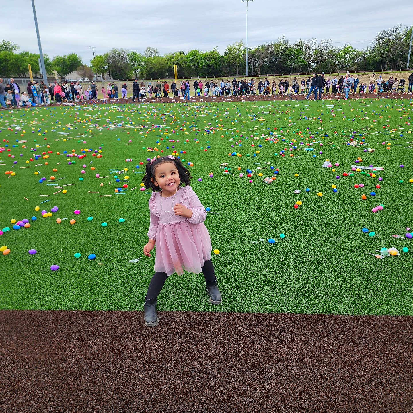 Joelee joined the competition — help win amazing prizes! child, girl, pink_dress, grass, field, colorful, plastic_eggs, crowd, outdoor, playful, smiling, event, people, overcast_sky, fun, celebration, young, boots, greenery, joy