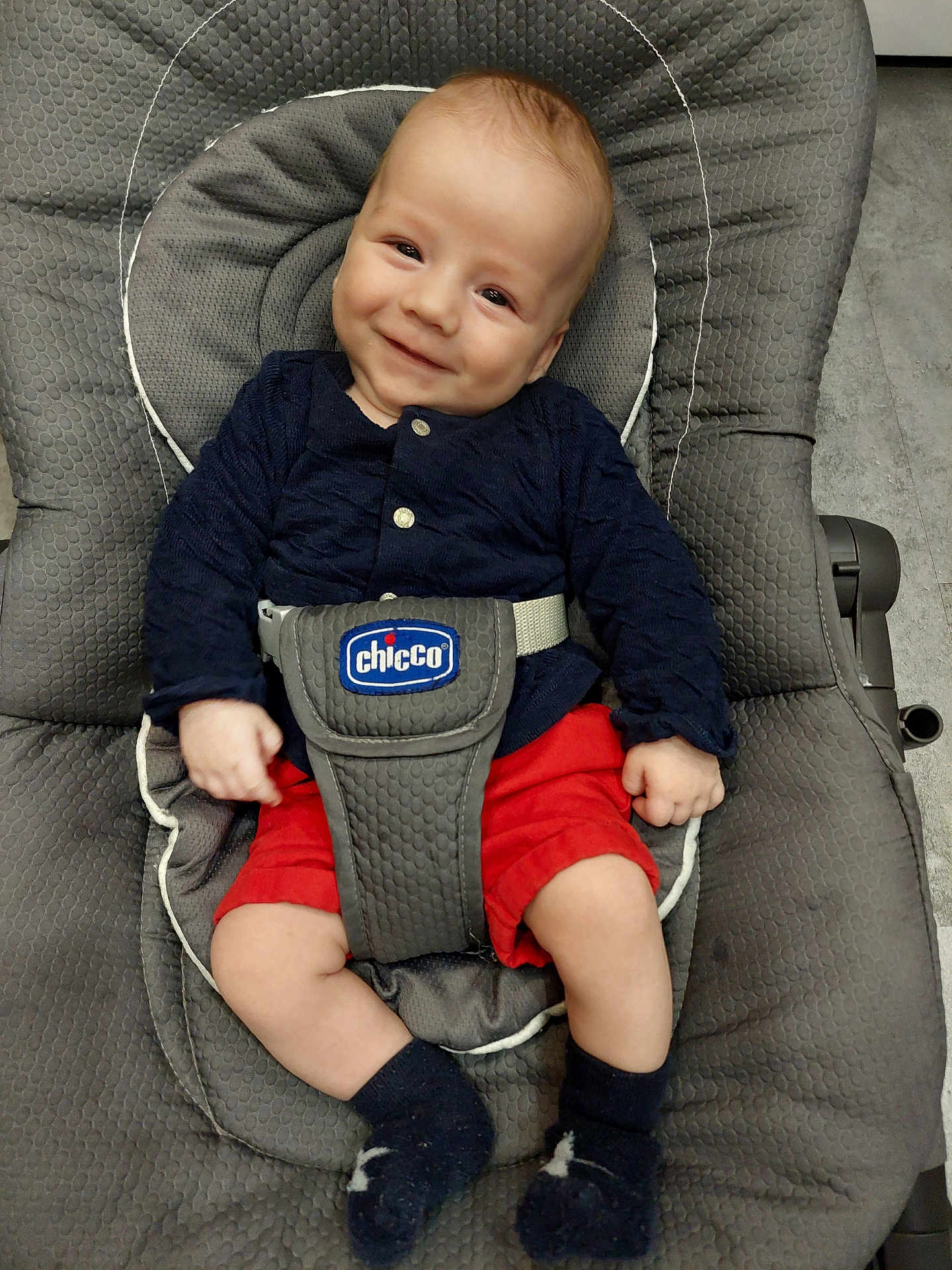 Jules a rejoint le concours — aidez-le/la à gagner de superbes lots ! baby, child, smiling, face, infant, clothing, red_shorts, navy_top, socks, baby_chair, chicco, indoor, padded_seat, cute, happy, person, portrait, seatbelt, comfort, floor