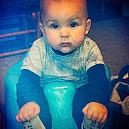 Braedyn joined the competition — help win amazing prizes! baby, child, infant, blue_seat, socks, clothing, indoor, carpet, face, hands, footwear, person, cute, seated, looking_at_camera, floor, toy, furniture, home, expression