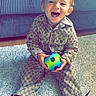 toddler, child, smiling, ball, toy, sitting, indoor, carpet, rug, couch, footwear, sneakers, patterned_clothing, happy, playful, young_child, portrait, casual, home, cute