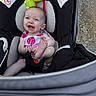 baby, car_seat, smiling, happy, infant, foot, plush_toy, ladybug, outdoor, gravel, child, seat_belt, clothing, person, cute, head, sitting, playful, toy, bright