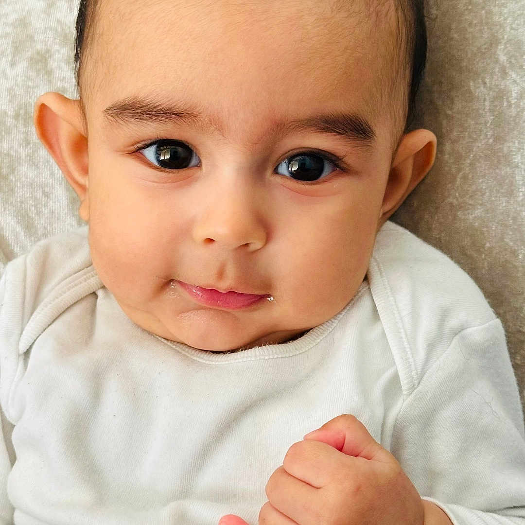 Jahred participe au concours pour gagner de l'argent avec cette photo : baby, child, clothing, couch, cute, expression, eyes, face, fist, hair, hand, indoors, infant, onesie, person, pillow, portrait, resting, skin, young