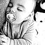 baby, sleeping, pacifier, cushion, plush_toy, panda, blanket, clothing, hand, face, infant, cozy, resting, indoors, closeup, peaceful, cute, child, soft, portrait