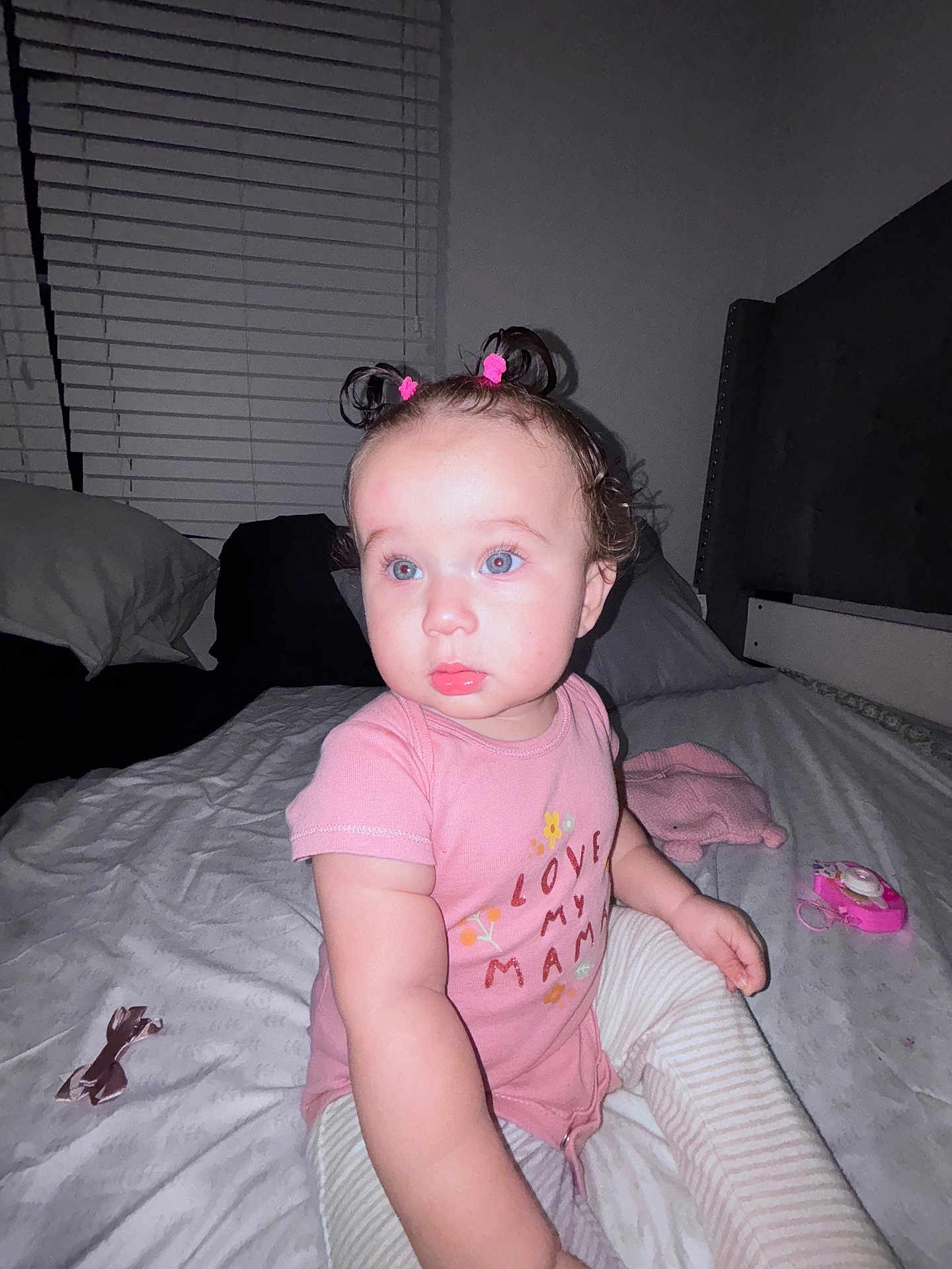 Madisson joined the competition — help win amazing prizes! toddler, child, baby, blue_eyes, pink_shirt, striped_pants, bed, pillow, toy, hair_ties, indoor, portrait, cute, sitting, person, face, window_blinds, furniture, bedroom, clothing