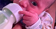 Asaiah joined the competition — help win amazing prizes! baby, bottle, child, closeup, cute, eyes, face, feeding, fingers, hand, holding, human, infant, milk, newborn, onesie, person, portrait, skin, warm