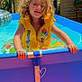 child, curly_hair, life_jacket, swimming_pool, inflatable_ring, outdoor, summer, water, play, smile, happy, sunlight, blue, yellow, fence, garden, toy, fun, person, vacation