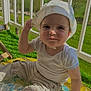 toddler, child, hat, sunhat, outdoor, greenery, playmat, grass, balcony, railing, pants, shirt, smile, face, hand, sunlight, daylight, nature, baby, portrait